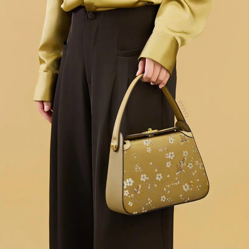 Side view of model carrying the Luxury Chinoiserie Song Brocade Magpie & Plum Blossom Handbag by hand.
