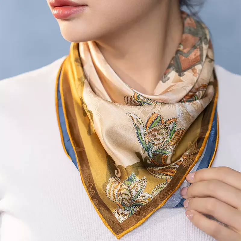 Model wearing a Luxury Nanjing Brocade Bloom double-sided mulberry silk square scarf around the neck, showing gold and blue floral details.