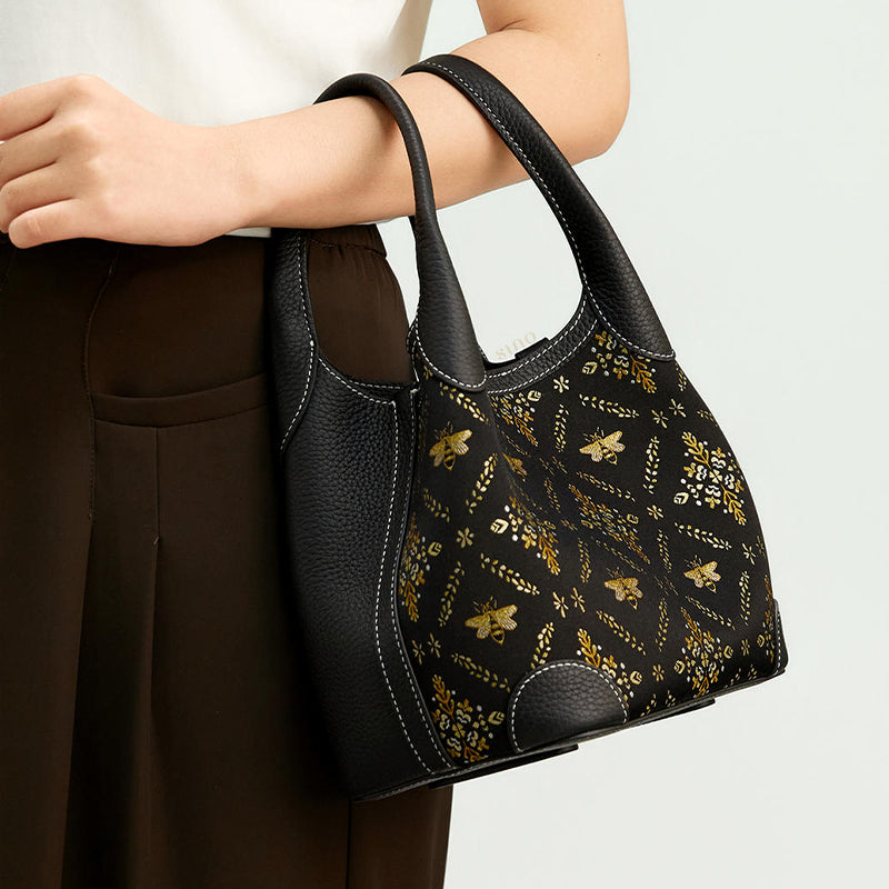 Handheld model view of the Luxury Shu Brocade Gilded Jade Leather Basket Tote Bag, highlighting the bee motif, leather handles, and elegant daily styling.