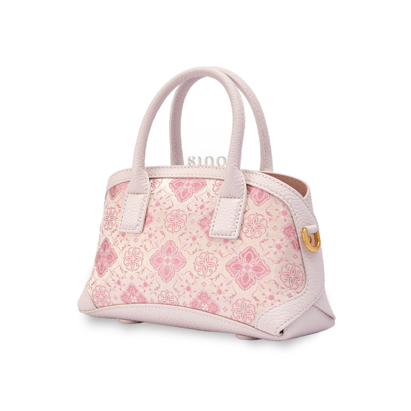 Angled view of the Luxury Shu Brocade Pink Persimmon Calyx Leather Top Handle Bag showing its structured silhouette and pink persimmon calyx brocade design.