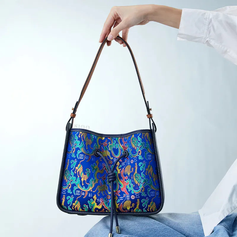 Model sitting with Shu brocade guardian blessing motif shoulder bag on knee.