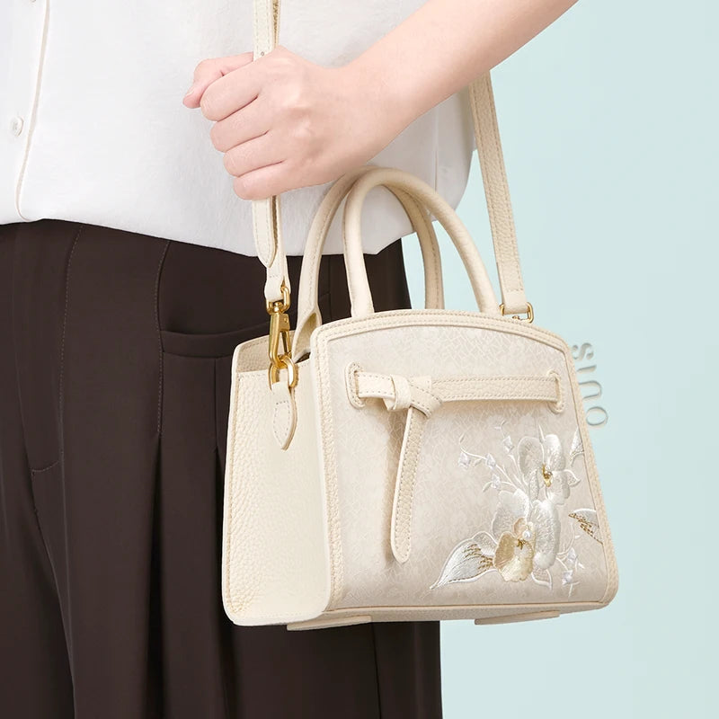Model wearing the Luxury Shuanglin Silk Orchid Butterfly Embroidered Leather Top Handle Bag with a shoulder strap, showing its versatile top handle and crossbody-style carry.