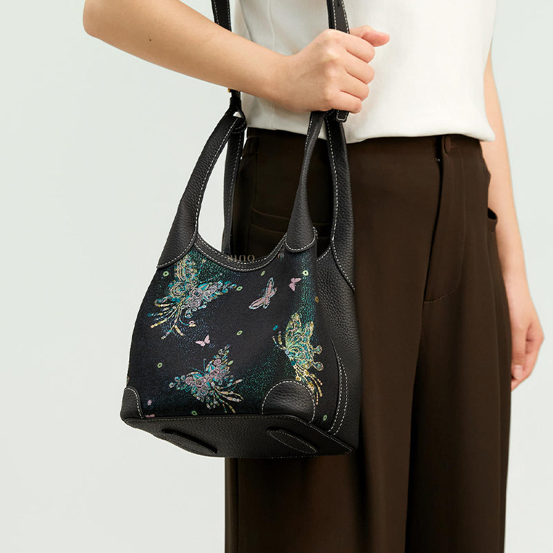 Model carrying the Luxury Song Brocade Butterfly & Pearl Leather Basket Tote Bag, showing the soft basket tote shape, black leather trim, and shimmering brocade design.