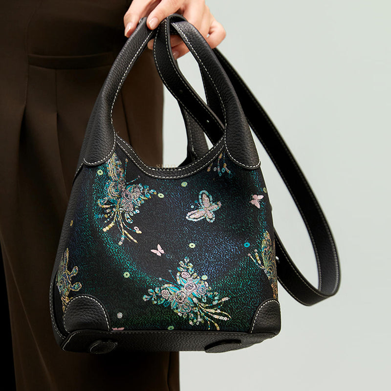Close-up model view of the Luxury Song Brocade Butterfly & Pearl Leather Basket Tote Bag, highlighting the butterfly motif, black leather handles, and adjustable long strap.