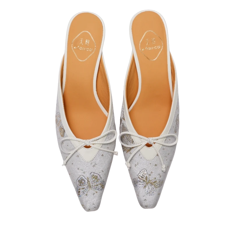 Transparent top view of Luxury Song Brocade Butterfly Reverie kitten heel mules for women featuring ivory brocade fabric, butterfly embroidery motifs, pointed toes, bow details, and elegant Chinese craftsmanship.