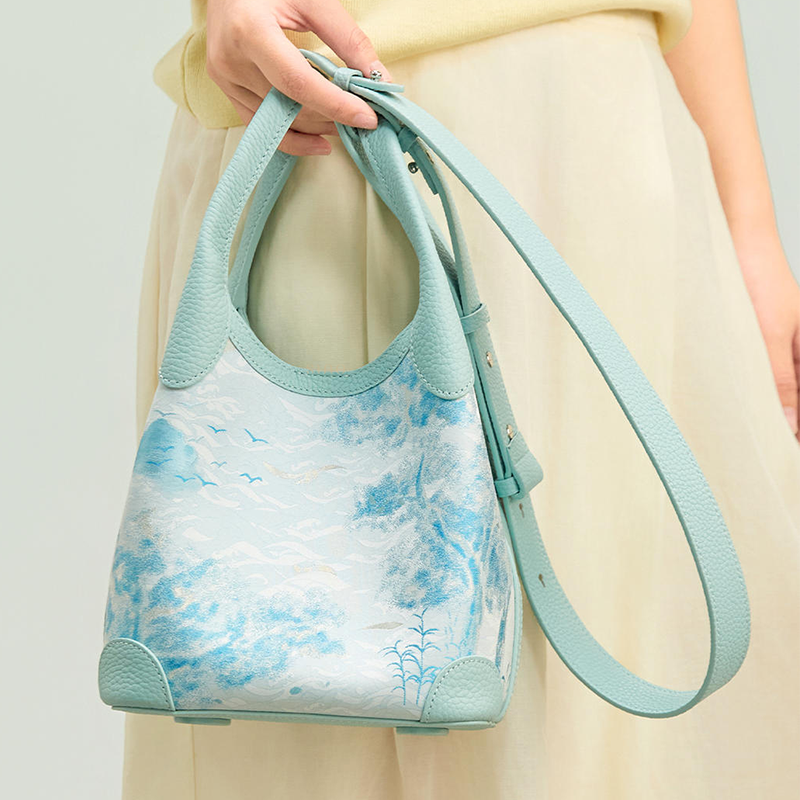 Close-up model view of the Luxury Song Brocade Misty Mountain Forest Leather Basket Tote Bag, showing the misty mountain and forest motif, leather handles, and adjustable long strap.