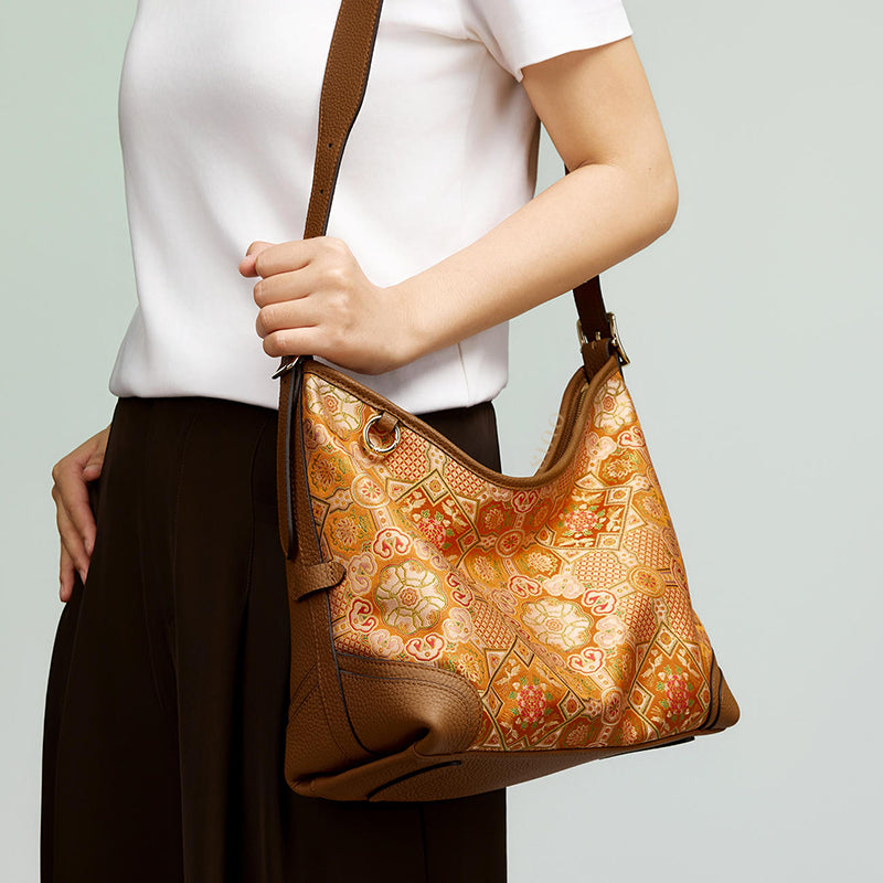 Front model view of the Luxury Song Brocade Orange Peony Motif Leather Crossbody Bag, highlighting the curved silhouette, orange brocade pattern, and shoulder strap.