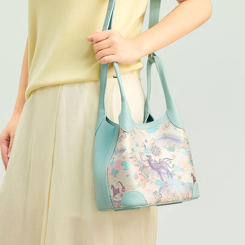 Model carrying the Chinoiserie Luxury Song Brocade Silk Road Leather Basket Tote Bag, showing the light blue leather trim and soft basket tote shape.