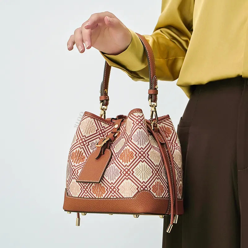 Model carrying bucket bag in arm crook position.
