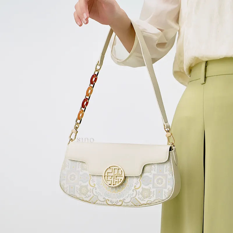Model carrying a luxury brocade handbag on her arm, with arm slightly lifted and relaxed.