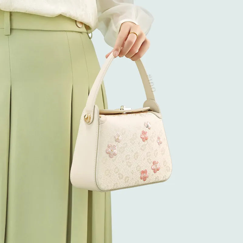 Model carrying silk handbag with single hand.