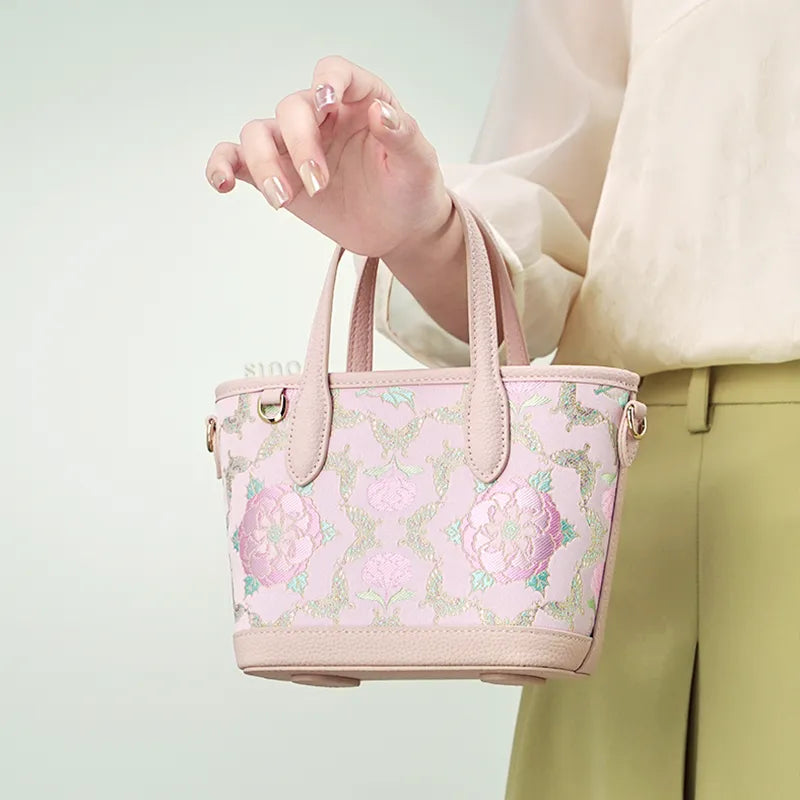 Model carrying shu brocade luxury crossbody bag with single hand.