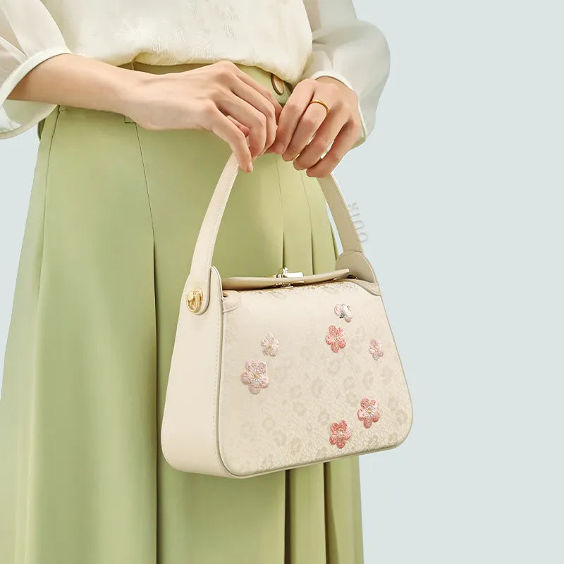 Model holding handbag with both hands at front.