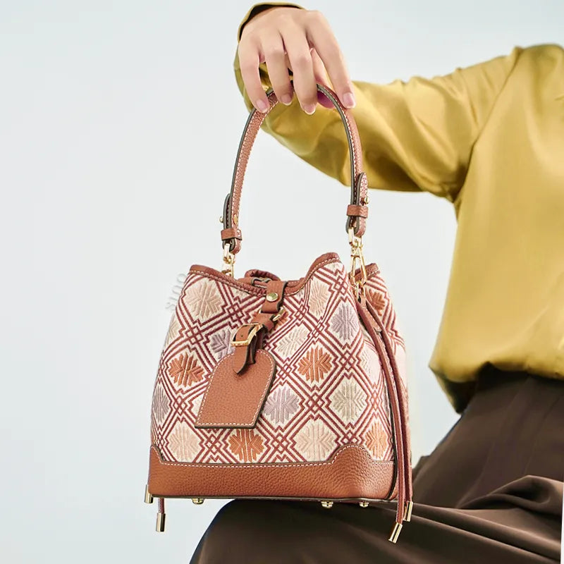 Seated model holding brocade bucket bag on knees.