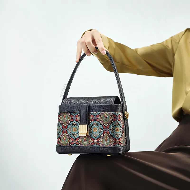 Seated model with brocade bag resting on knees.