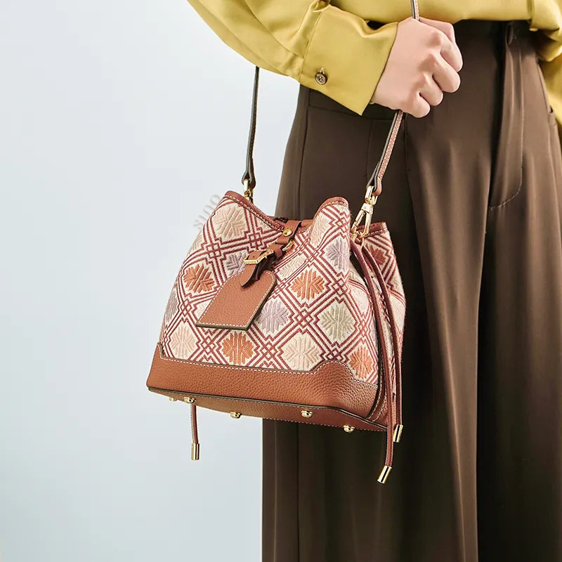 Model wearing brocade bucket bag on shoulder.