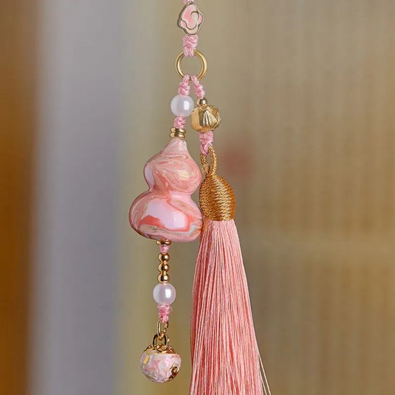 Auspicious pink Daqi lacquer Hulu tassel bag charm hanging with marbled details, pearl accents, and a long pink tassel.