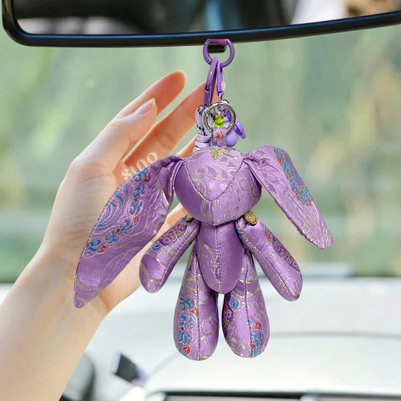 Handheld purple Jade Rabbit bag charm made of handmade Yunjin brocade, showing its long ears, soft padded body, and decorative hanging details.