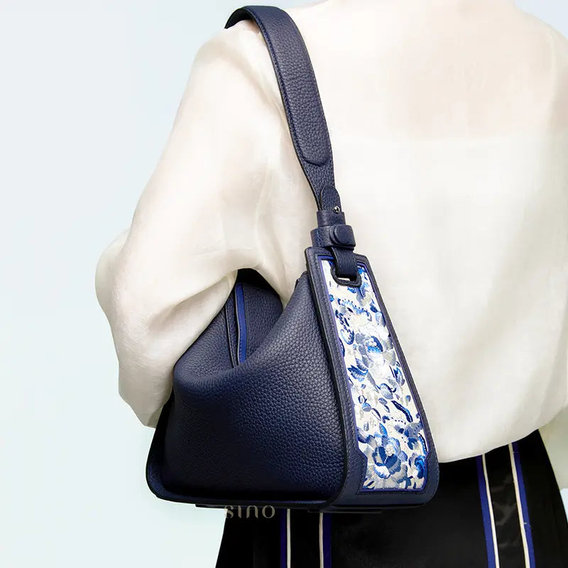 Woman wearing a SANLAN embroidered blue floral panel blue leather shoulder bag for elegant everyday styling.