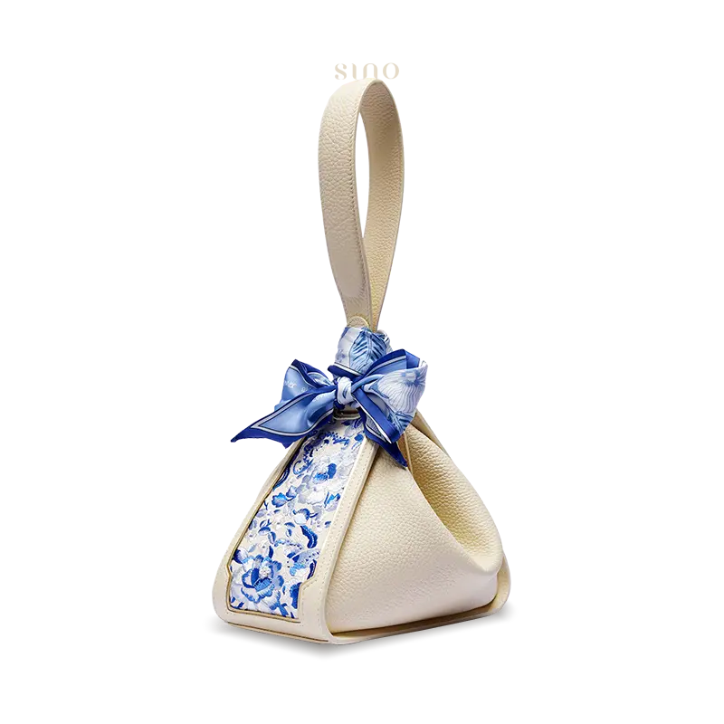 Side view of a beige Zongzi handbag with blue SANLAN floral embroidery and a decorative silk scarf.