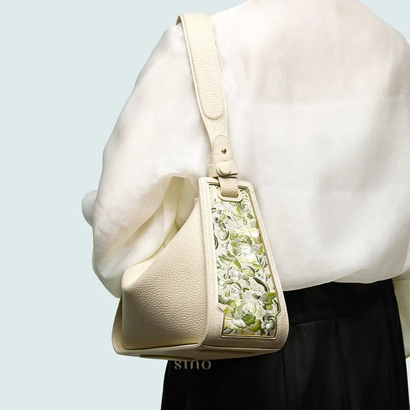 Woman wearing a SANLAN green floral panel beige leather shoulder bag for elegant everyday styling.