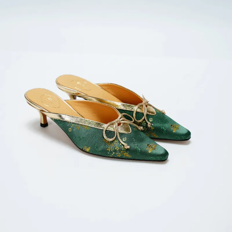 Close-up detail of Shu Brocade emerald mules showcasing gilded butterfly pattern and silk woven texture.