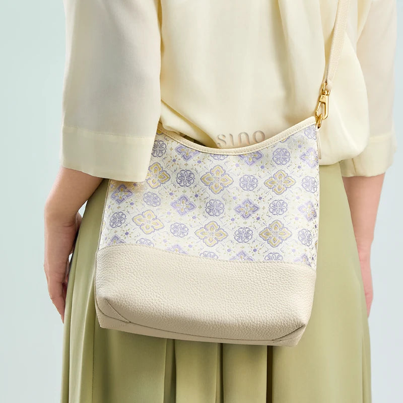 Back view of a model wearing the Shu Brocade Persimmon Calyx leather shoulder bag with an adjustable strap.