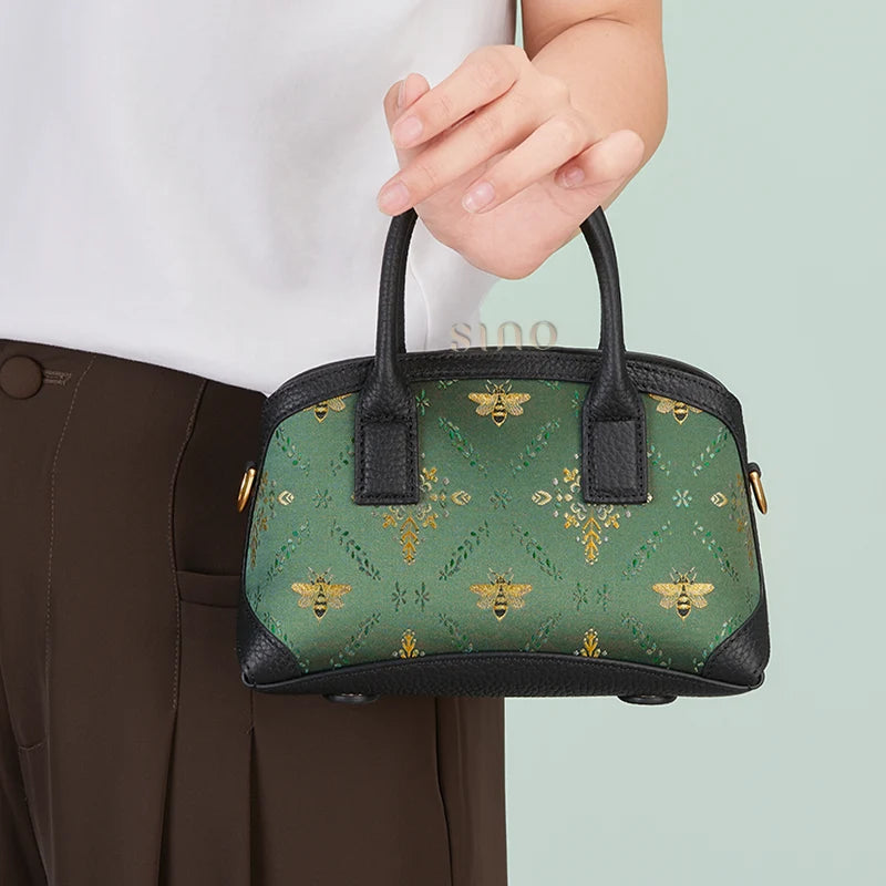 Front lifestyle view of the Shu Brocade Verdant Layers Leather Top Handle Bag carried by hand.