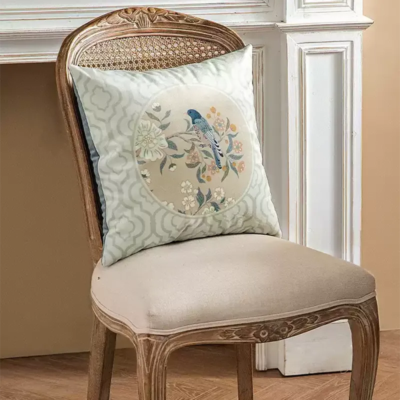 Chinoiserie luxury floral birds pillow on chair, side view.