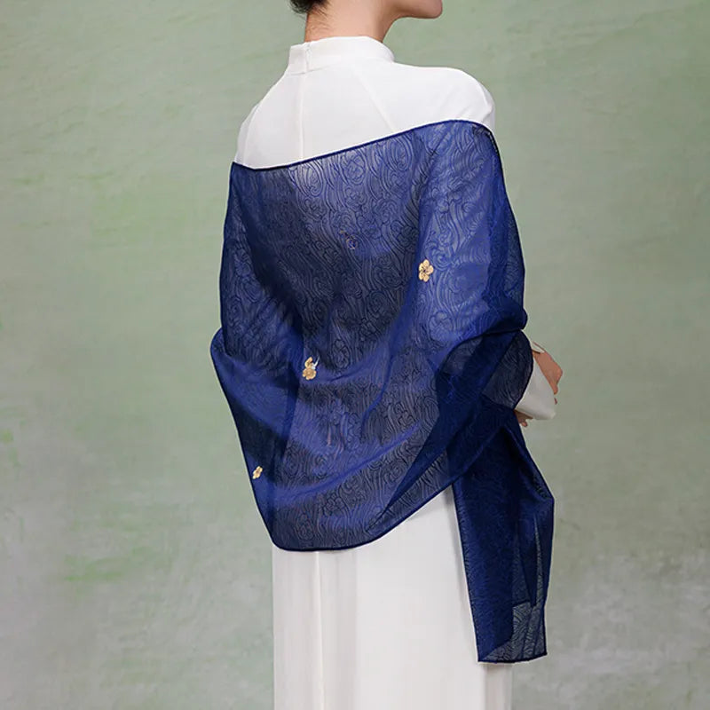 Back view of a deep blue Nanjing Yunjin mulberry silk shawl draped across the shoulders, revealing its semi-sheer fabric, flowing patterns, and gold floral accents.