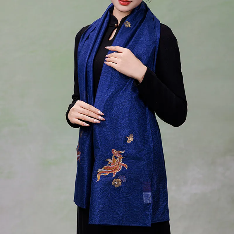 Front view of a handcrafted Nanjing Yunjin silk shawl draped over a black outfit, highlighting its blue woven texture and ornamental fish design.