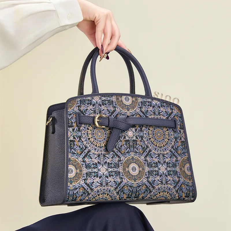 Seated model holding the Song Brocade Bada Yun motif leather top handle bag.