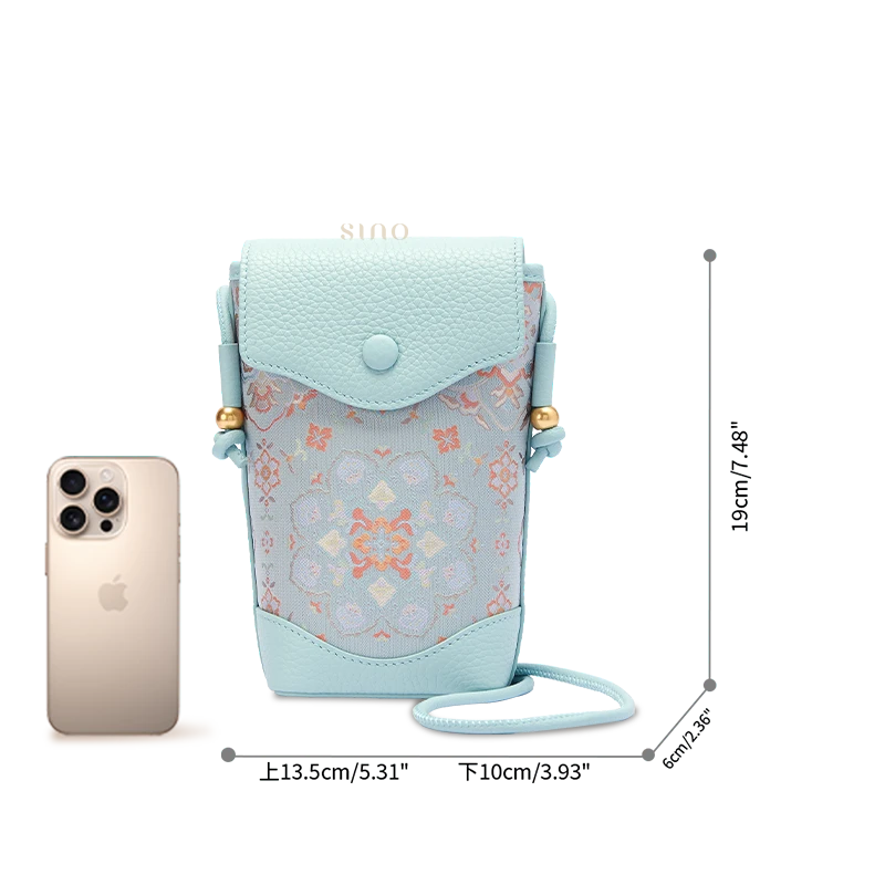 Song Brocade crossbody phone bag size reference showing its compact dimensions beside a smartphone.