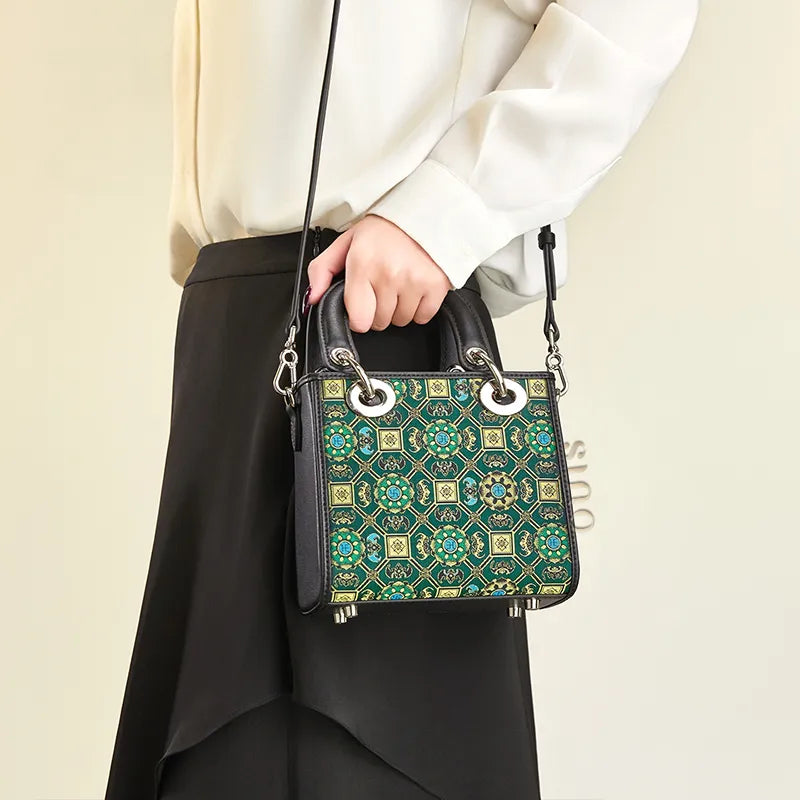 Model holding the Song Brocade Lotus and Auspicious motif mini crossbody bag by the handle.
