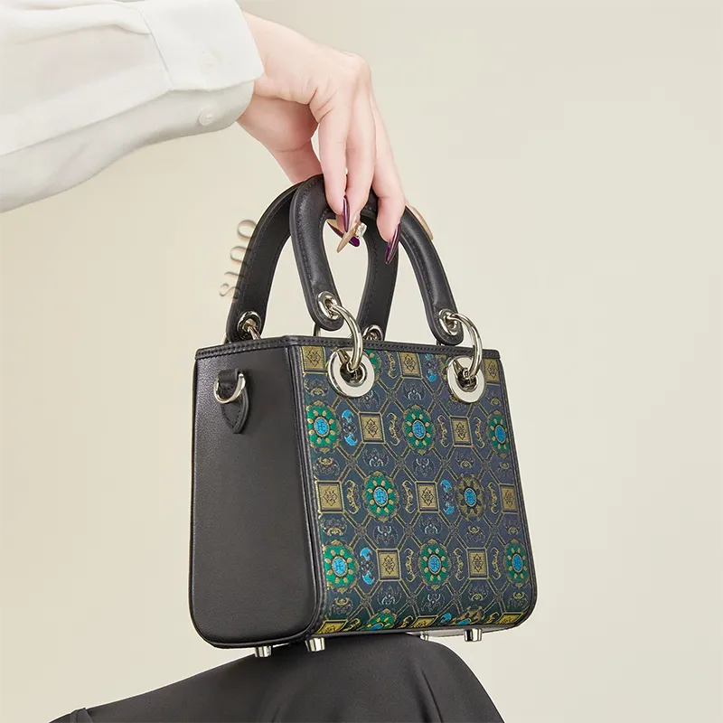 Seated model holding the Song Brocade Lotus and Auspicious motif mini crossbody bag.