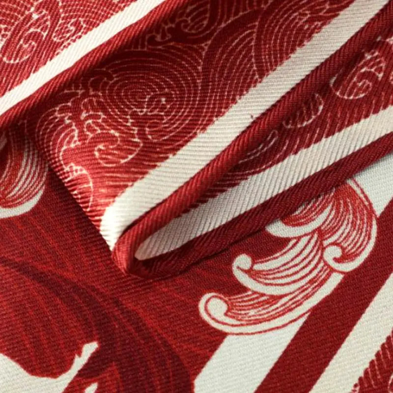 Close-up of the finely finished edge on the Steed Across the Tides Mulberry Silk Square Scarf with detailed red and ivory wave motifs