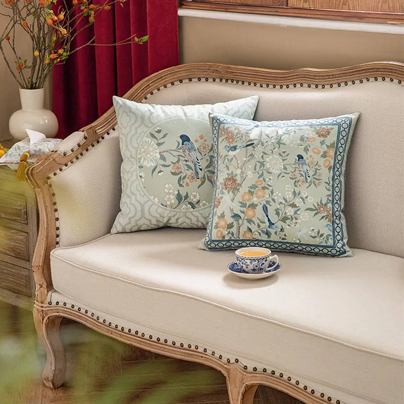 White A&B style embroidered pillows on a sofa.