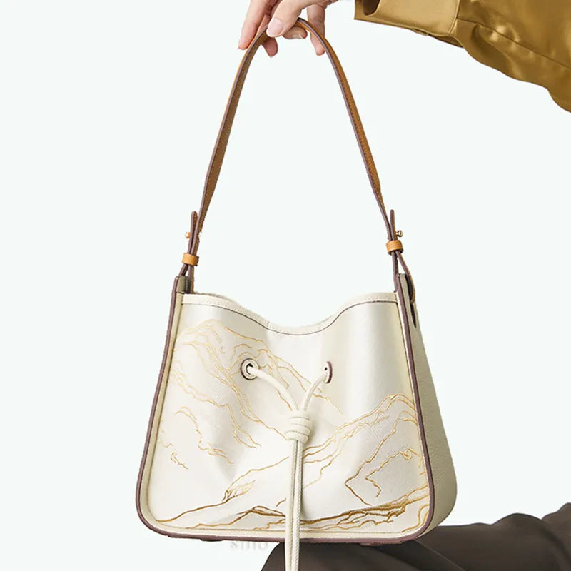 Model sitting with Zen of Mountains brocade shoulder bag on knee.