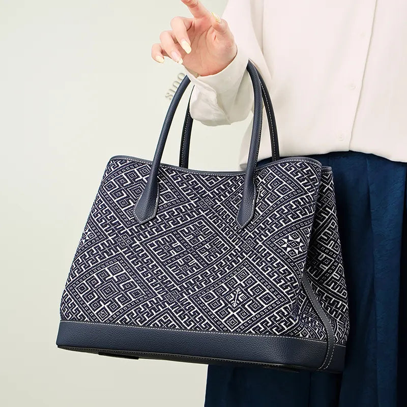 Stylish model in a blue dress wearing the Zhuang Brocade Embroidered Leather Shoulder Bag on one shoulder, demonstrating its versatile carry style.