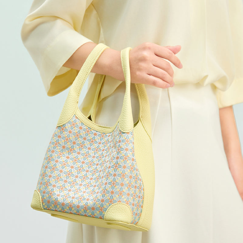 Model carrying the Luxury Zhuang Brocade Osmanthus Motif Leather Basket Tote Bag, showing the soft basket tote shape, pale yellow leather trim, and delicate brocade pattern.
