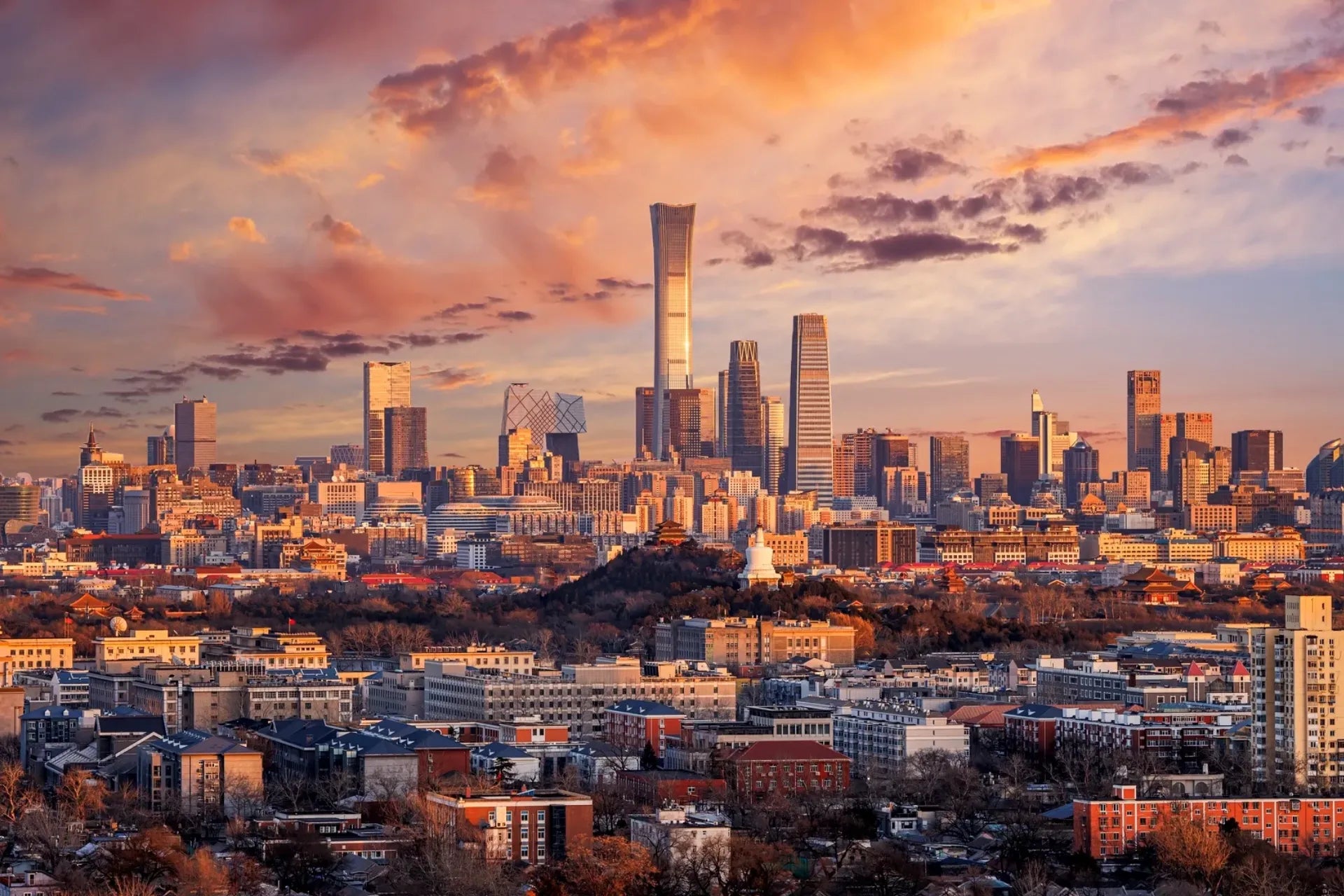 Beijing CBD skyline at sunset, where modern skyscrapers rise above the historic cityscape.