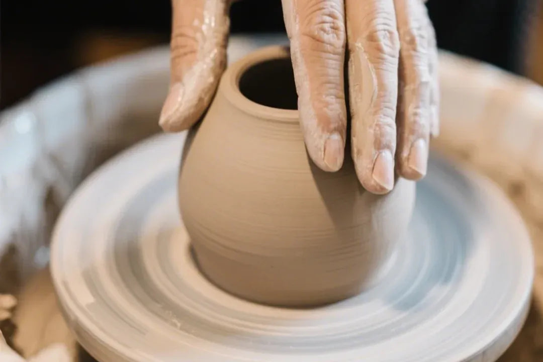 Artisan hands molding a clay vessel on a potter's wheel—traditional Chinese ceramic craft.