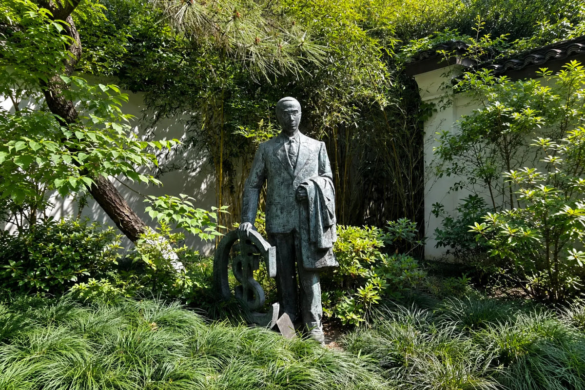 Statue of Du Jinsheng, pioneer of Chinese pictorial brocade, standing among bamboo and greenery in Hangzhou.