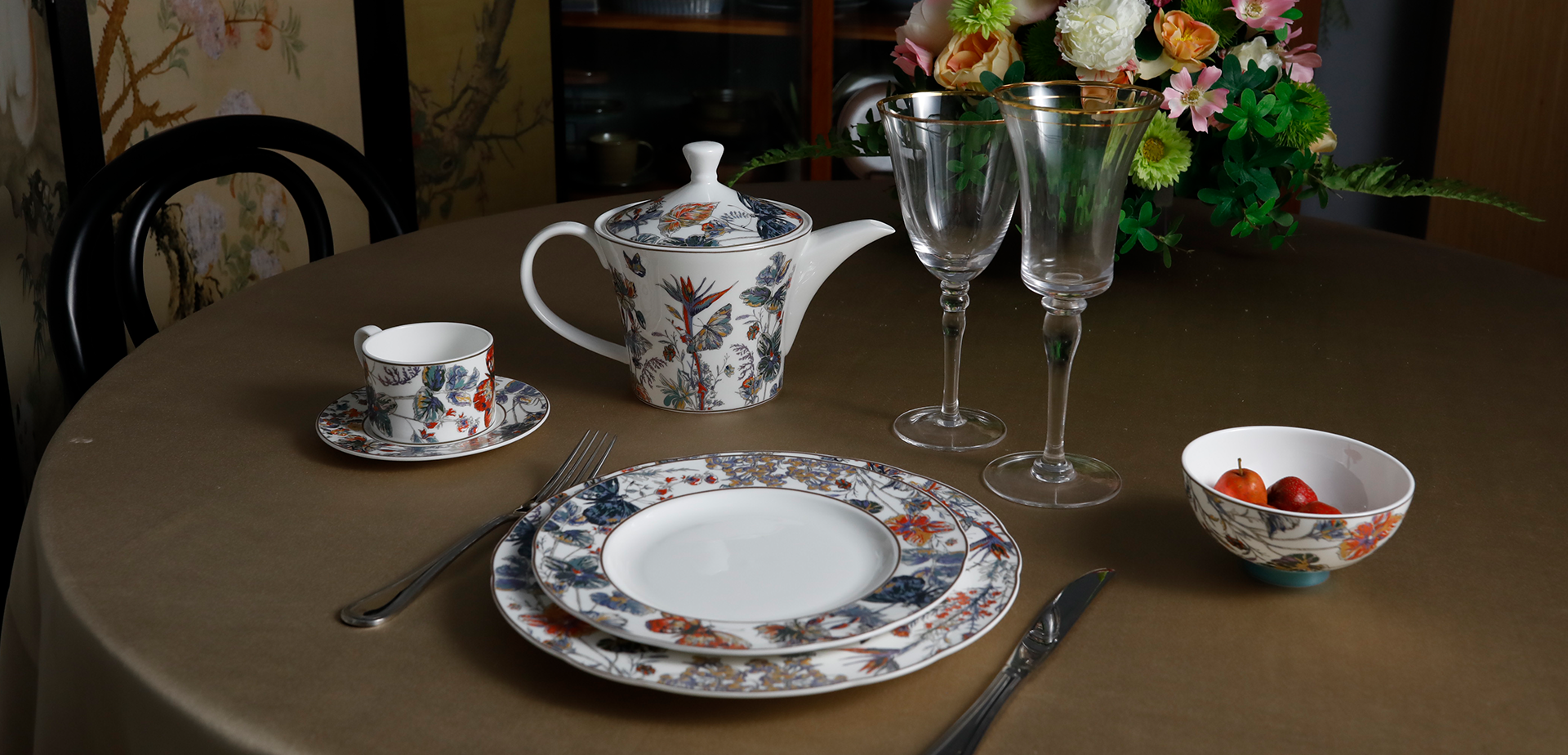 Elegant Sino Porcelain teaware (teapot, cup, saucer) on a table with floral accents, showcasing the Teaware collection.