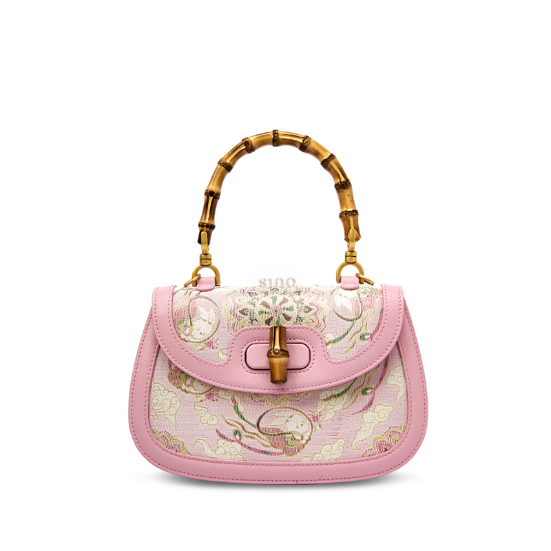Front view of a pink Song brocade handbag made from mulberry silk, featuring a bamboo handle and intricate floral embroidery.