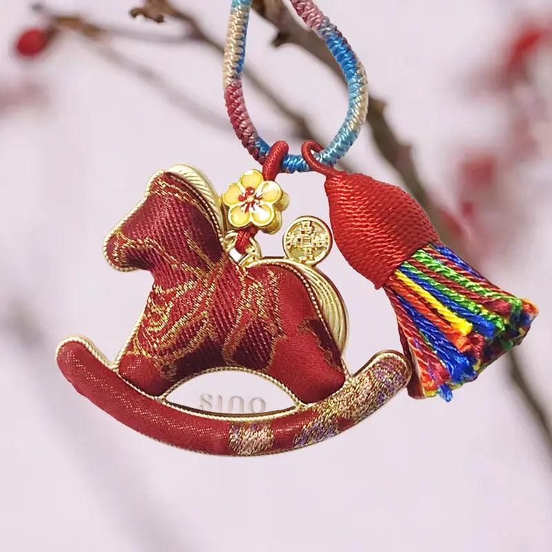 Auspicious red Yunjin brocade rocking horse bag charm displayed with a colorful hanging loop and multicolor tassel.