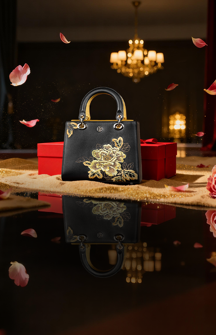 Black Friday sale banner: Black luxury handbag with golden peony embroidery, red gift box, and falling pink petals.