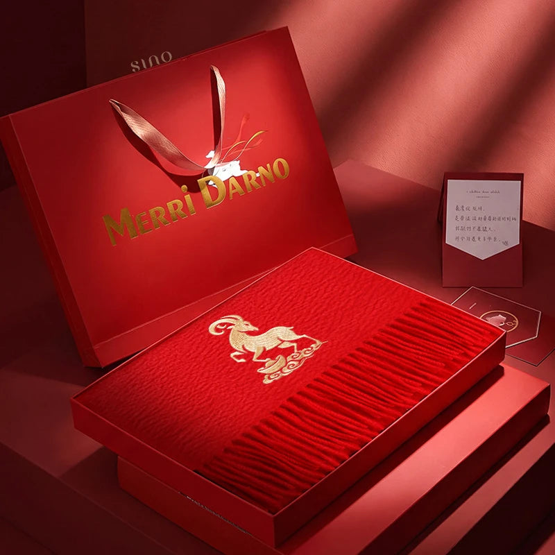 Bright red cashmere scarf featuring gold goat embroidery, neatly presented in an open red gift box with matching luxury packaging.