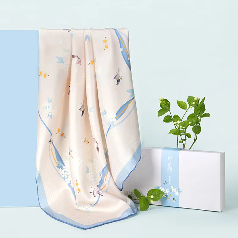 Butterfly Dream Print Mulberry Silk Square Scarf displayed with its beige background, colorful butterfly motifs and blue border.