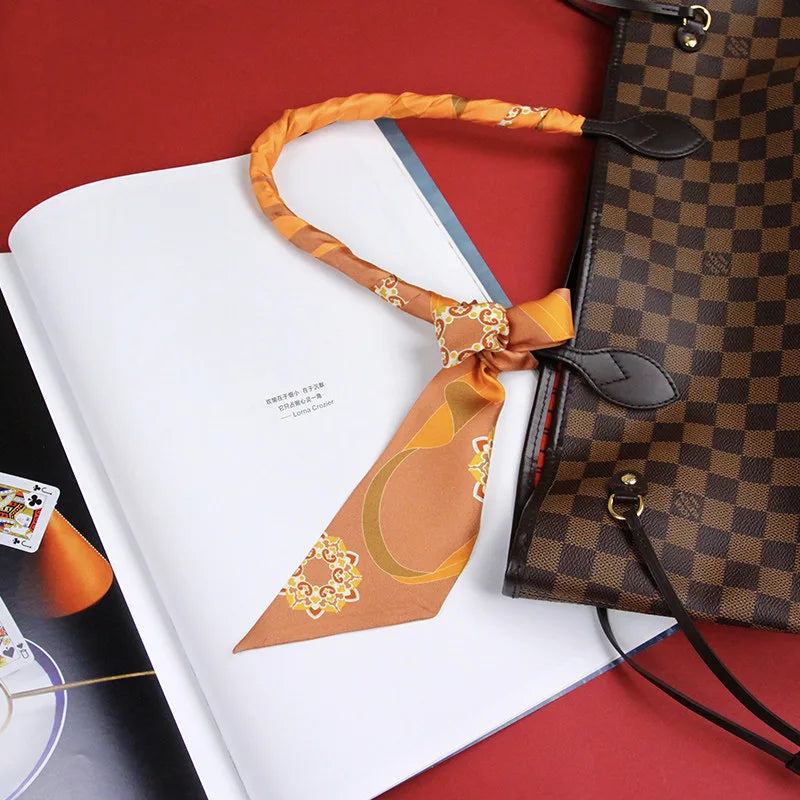 Chinese Dunhuang Motif Print Mulberry Silk Twilly 160x7.3 cm tied on a handbag handle as a chic accessory with orange Dunhuang motif print.